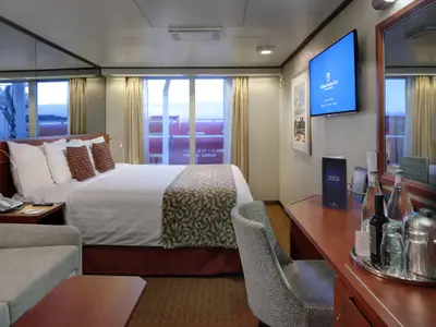 Blick in eine gemütliche Außenkabine mit Doppelbett und Schreibtisch an Bord der Nieuw Amsterdam.