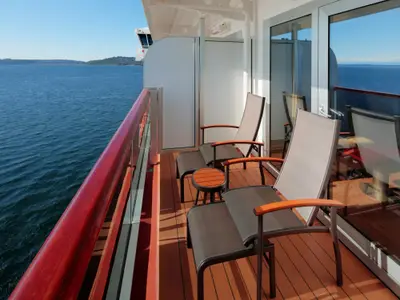 Balkon einer Kabine an Bord der Nieuw Amsterdam mit zwei bequemen Liegestühlen und freiem Blick auf das blaue Meer.