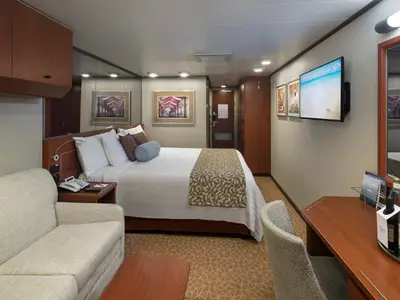 Komfortable Balkonkabine an Bord der Nieuw Amsterdam mit einem großen Bett, Sofa, Schreibtisch und Flachbildfernseher.