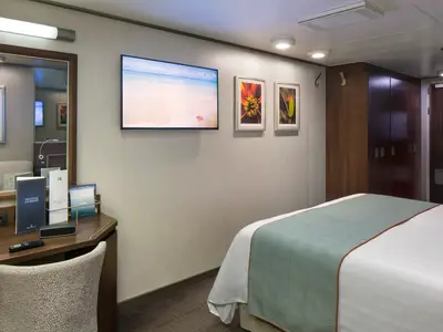Gemütliche Balkonkabine an Bord der Nieuw Amsterdam mit einem Doppelbett, Flachbildfernseher und Schreibtisch.