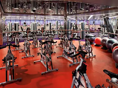 Das moderne Fitness Center an Bord der Nieuw Amsterdam mit zahlreichen Spinning-Bikes auf rotem Boden.