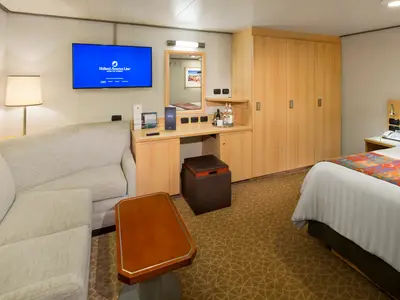 Eine gemütliche Standard-Innenkabine an Bord der Nieuw Amsterdam mit einem Sofa, einem Schreibtisch, einem TV und einem bequemen Doppelbett.