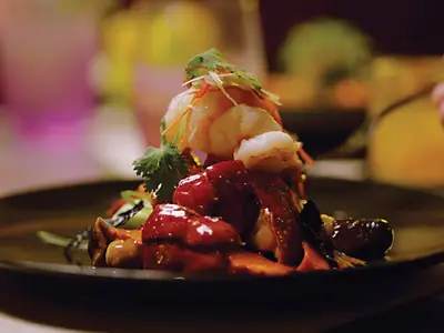 Ein elegant angerichtetes asiatisches Gericht mit Shrimps und Beilagen im Restaurant Tamarind an Bord der Nieuw Amsterdam.