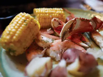 Nahaufnahme eines Meeresfrüchte-Tellers mit Krabbenscheren, Shrimps und Maiskolben an Bord der Nieuw Amsterdam.