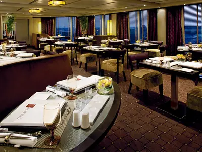 Eingedeckte Tische im stilvollen Tamarind Restaurant an Bord der Nieuw Amsterdam mit Blick auf das Meer bei Abenddämmerung.