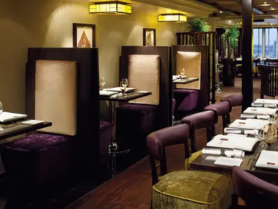 Elegante Tische und violett gepolsterte Sitznischen im gehobenen Restaurant an Bord der Nieuw Amsterdam.