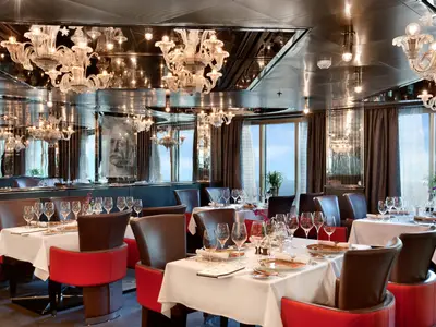Elegant eingedeckte Tische mit Kristallleuchtern und Polstersesseln im Pinnacle Grill an Bord der Nieuw Amsterdam.
