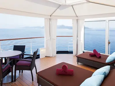 Sonnendeck-Bereich mit stilvollen Cabanas, Liegestühlen, Sitzecke und freiem Meerblick an Bord der Nieuw Amsterdam.