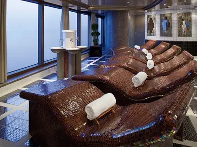 Beheizte Mosaik-Entspannungsliegen mit weißen Handtüchern im Thermal-Suite-Bereich an Bord der Nieuw Amsterdam.