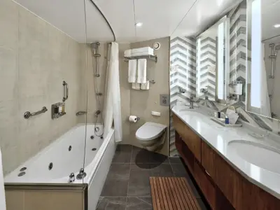Blick in das luxuriöse Badezimmer einer Spa-Suite an Bord der Nieuw Amsterdam mit Badewanne, Doppelwaschbecken und WC.