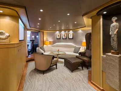 Blick in den eleganten Wohnbereich der Pinnacle Suite an Bord der Nieuw Amsterdam mit stilvollen Möbeln und Skulpturen.