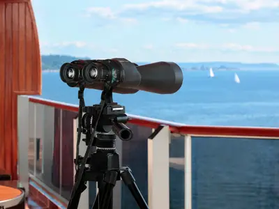 Ein Fernglas auf einem Stativ auf dem Balkon der Pinnacle Suite an Bord der Nieuw Amsterdam mit Blick auf das Meer.