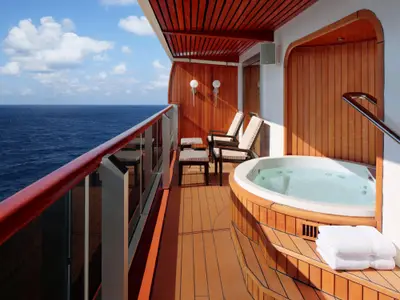 Balkon der Pinnacle Suite an Bord der Nieuw Amsterdam mit Whirlpool, Holzverkleidung, Liegestühlen und Meerblick.
