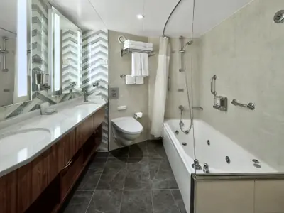 Das Badezimmer einer Suite an Bord der Nieuw Amsterdam zeigt einen Doppelwaschtisch, ein WC und eine Badewanne.