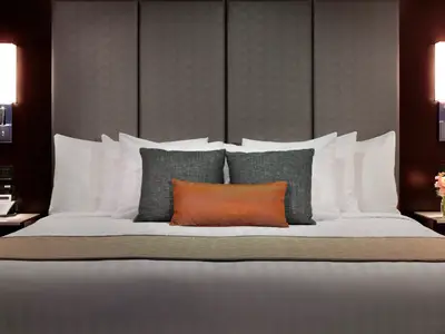 Das elegant bezogene Mariner's Dream Bett mit grauem Kopfteil und Kissen in einer Suite an Bord der Nieuw Amsterdam.
