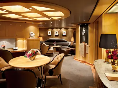 Der großzügige Wohn- und Essbereich der Pinnacle Suite an Bord der Nieuw Amsterdam mit edlen Holzmöbeln und Kunstwerken.