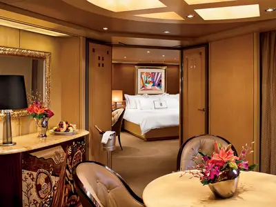 Innenansicht einer elegant eingerichteten Suite an Bord der Nieuw Amsterdam mit Blick auf das gemütliche Doppelbett.