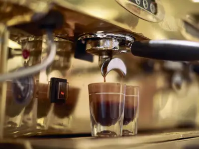 Nahaufnahme einer Espressomaschine im Grand Dutch Cafe an Bord der Nieuw Statendam, die Kaffee in zwei Gläser füllt.