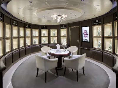 Blick in den runden, eleganten Schmuckladen von Effy an Bord der Nieuw Statendam mit Vitrinen, Tisch und vier weißen Sesseln.
