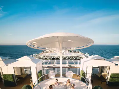Sonnendeck an Bord der Nieuw Statendam mit eleganten weißen Cabanas, Schattenspender und Ausblick auf das tiefblaue Meer.