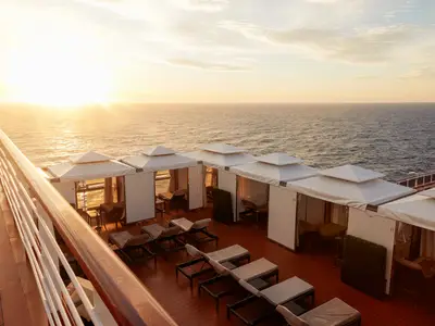 Blick auf luxuriöse Cabanas und Sonnenliegen an Bord der Nieuw Statendam bei Sonnenuntergang über dem weiten Meer.