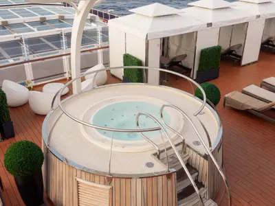 Ein runder Whirlpool mit Einstiegsleiter auf dem hölzernen Sonnendeck „The Retreat“ an Bord der Nieuw Statendam.