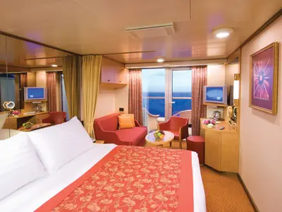Blick in eine gemütlich eingerichtete Balkonkabine an Bord der Noordam mit großem Bett, Sitzecke und Balkon zum Meer.