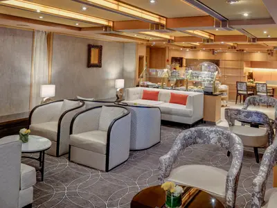 Blick in die elegant eingerichtete Neptune Lounge an Bord der Noordam mit gemütlichen Sesseln und Buffet.