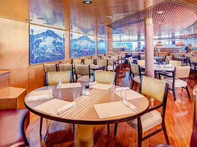 Elegant eingedeckte Tische mit Holzstühlen im Restaurant Canaletto an Bord der Noordam mit blau-weißen Wandfliesen.