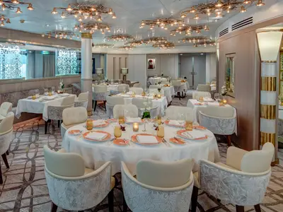 Der elegant eingerichtete Pinnacle Grill an Bord der Noordam mit runden, festlich gedeckten Tischen und moderner Lichtinstallation an der Decke.