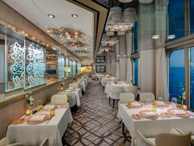 Elegantes Restaurant Pinnacle Grill an Bord der Noordam mit stilvoll gedeckten Tischen und Blick auf das Meer durch große Fenster.