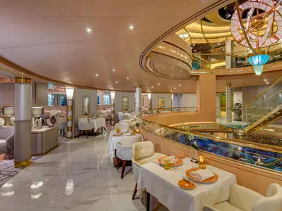 Einblick in das luxuriöse Pinnacle Grill Restaurant an Bord der Noordam mit gedeckten Tischen neben dem Atrium-Geländer.