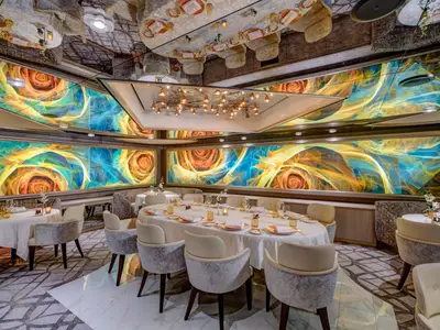 Das elegante Restaurant Pinnacle Grill an Bord der Noordam mit weiß gedeckten Tischen und farbenfrohen Kunstwerken an den Wänden.
