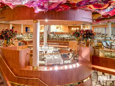 Der stilvolle, mehrstöckige Hauptspeisesaal an Bord der Noordam mit festlich gedeckten Tischen und warmem Licht.