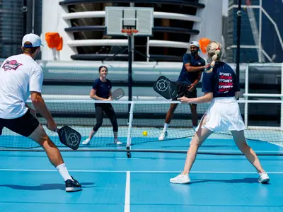 Vier Personen beim aktiven Pickleball-Spiel auf dem Sportplatz an Bord der Noordam.