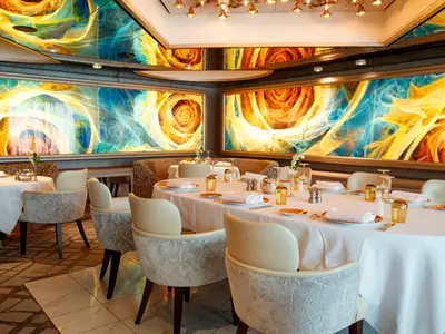 Der elegant eingedeckte Restaurantbereich an Bord der Noordam besticht durch farbenfrohe Kunstwerke an den Wänden und weiße Tischdecken.
