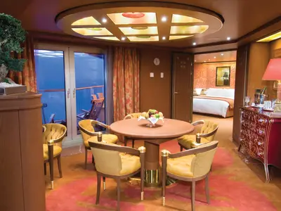 Ein Blick in die elegante Pinnacle Suite an Bord der Noordam mit einem Essbereich und angrenzendem Schlafzimmer.