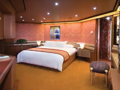 Blick in die elegante und geräumige Pinnacle Suite an Bord der Noordam mit einem großen Doppelbett.