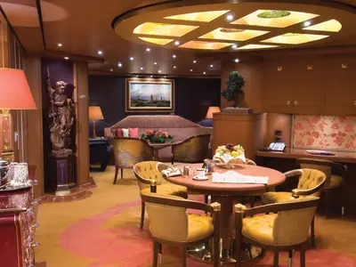 Blick in den großzügigen Wohnbereich der Pinnacle Suite an Bord der Noordam mit eleganten Sesseln und edler Holzvertäfelung.