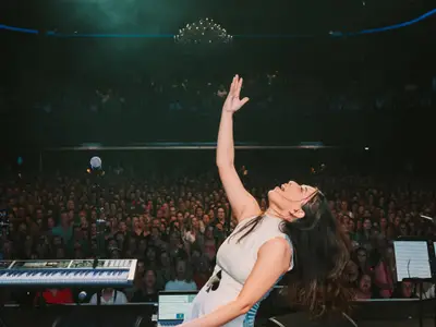 Sängerin Astrid Jorgensen singt mit erhobenem Arm auf der Bühne vor großem Publikum an Bord der Noordam.