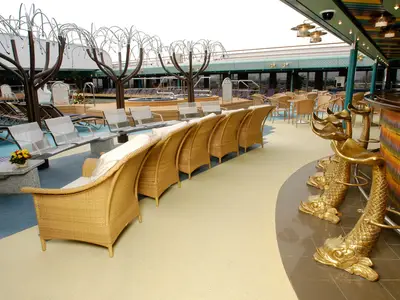 Die Lido Bar an Bord der Oosterdam zeigt goldene Barhocker in Fischform und gemütliche Korbsessel auf dem Pooldeck.