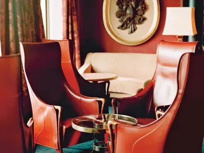 Nahaufnahme von eleganten roten Ledersesseln mit kleinen Tischen in der gemütlichen Explorer's Lounge an Bord der Oosterdam.