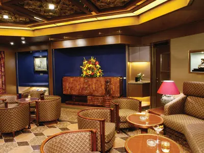 Blick in den eleganten Cigar Room an Bord der Oosterdam mit gemütlichen Sesseln, edlen Holzmöbeln und warmer Beleuchtung.