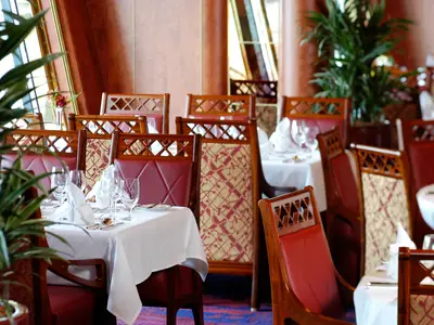 Festlich gedeckte Tische mit feinen Gläsern und roten Holzstühlen im Vista Dining Room an Bord der Oosterdam.
