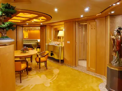 Die edel eingerichtete Pinnacle Suite an Bord der Oosterdam bietet einen Essbereich, edle Holzverkleidung und eine stilvolle asiatische Statue.