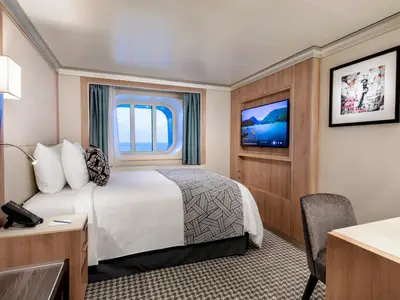 Eine hell eingerichtete Außenkabine an Bord der Rotterdam mit gemütlichem Doppelbett, Meerblick-Fenster, Fernseher und Schreibtisch.