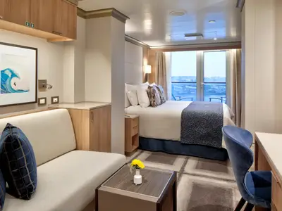 Eine geräumige Balkonkabine an Bord der Rotterdam mit modernem Sofa, einem bequemen Doppelbett und Balkonzugang.
