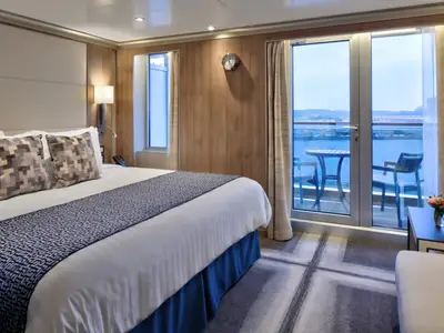 Gemütliche Balkonkabine an Bord der Rotterdam mit großem Bett und Schiebetür zum Balkon mit Meerblick.