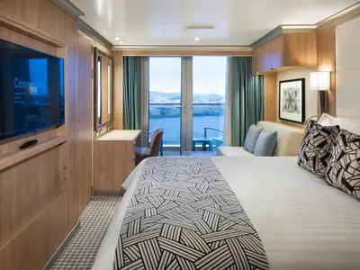 Eine gemütliche Balkonkabine an Bord der Rotterdam mit Doppelbett, Sofa, Schreibtisch und Blick auf das Meer durch die Balkontür.
