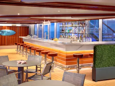 Blick auf die stilvoll beleuchtete Sea View Bar an Bord der Rotterdam bei Abenddämmerung mit Blick aufs Meer.